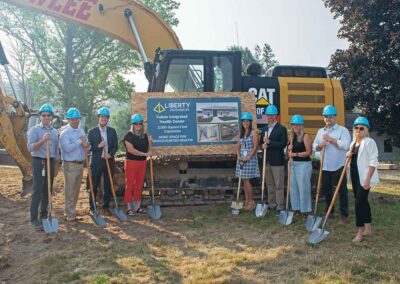People standing in front of a sign and a yellow construction vehicle.